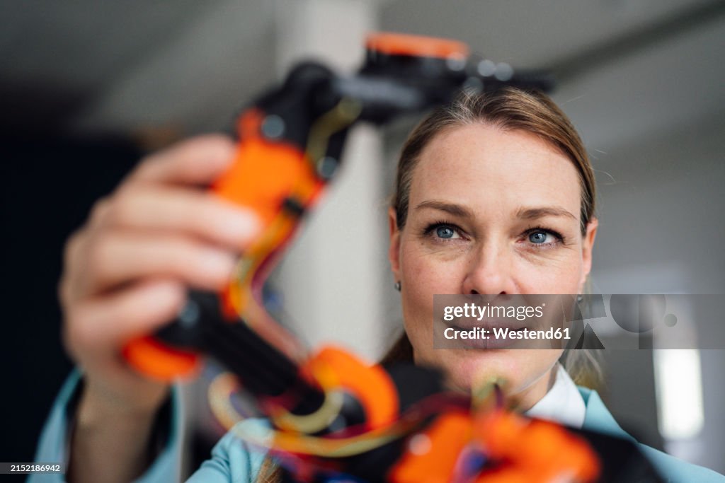 Smiling engineer examining robotic arm at office