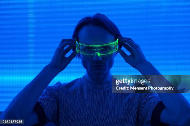 futuristic man with smart neon glasses in blue neon wall - person on computer in dark room foto e immagini stock