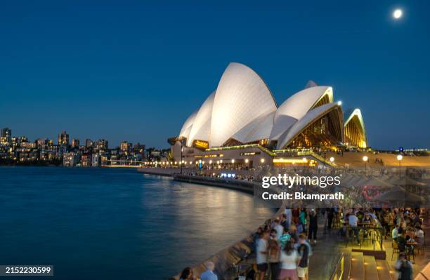 twilight settles in over the in the famous sydney harbor while people enjoy drinks and dinner in sydney australia - opera house stock pictures, royalty-free photos & images
