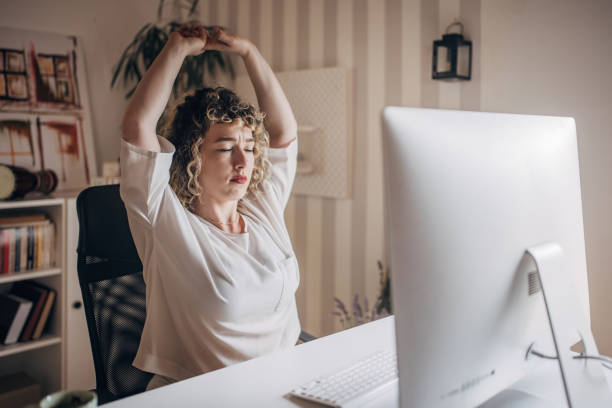 office worker taking a stretching break at desk - ergonomics office desk stock pictures, royalty-free photos & images