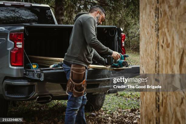 carpenter cutting wood behind pick up truck - kleinlastwagen stock-fotos und bilder