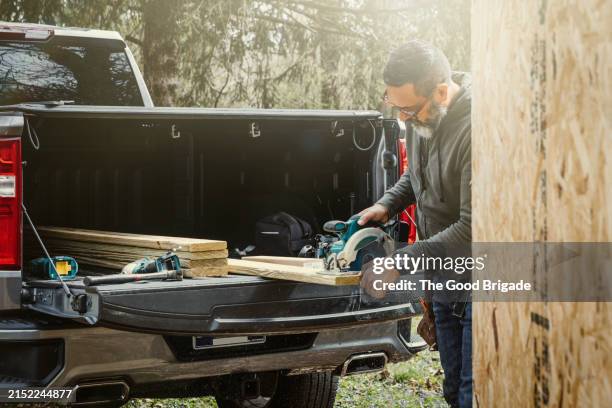 mature man using saw to cut plywood - pickup truck wood stock pictures, royalty-free photos & images