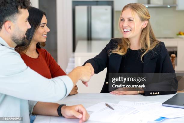 real estate or insurance agent or lawyer shaking hands with couple. they are signing home loan mortgage or contract documents. - estate agency stock pictures, royalty-free photos & images