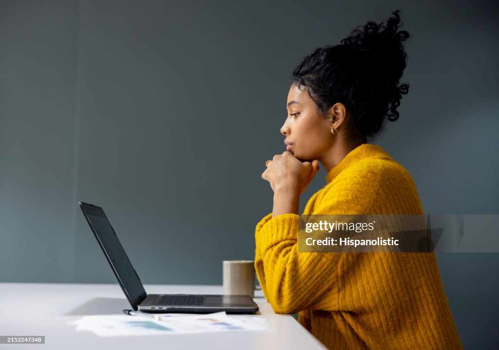 Mujer de negocios reflexiva trabajando en su computadora portátil en la oficina