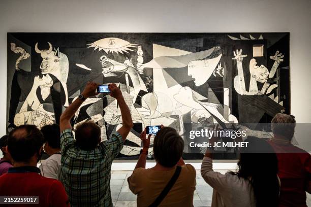Visitors look at and photograph Pablo Picasso's Guernica denouncing the atrocities of the Spanish Civil War at the Reina Sofia Museum in Madrid in...