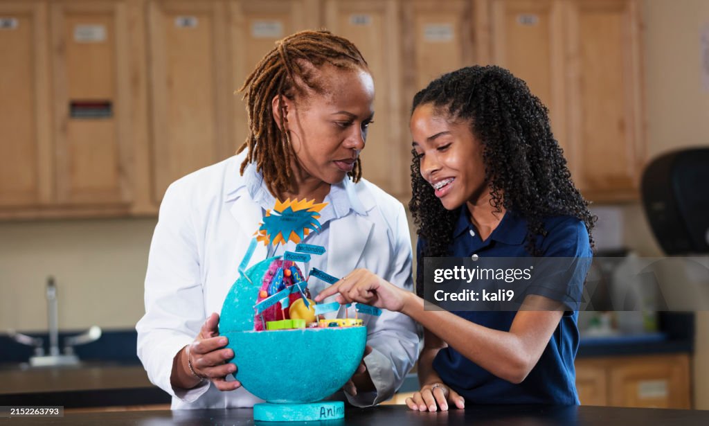 Student, teacher in science class with model of cell