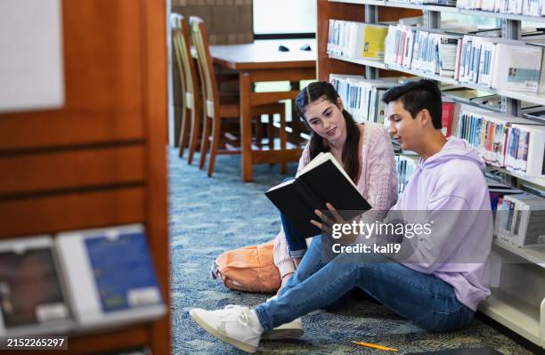 two high school students in library looking at book - boy library stock pictures, royalty-free photos & images