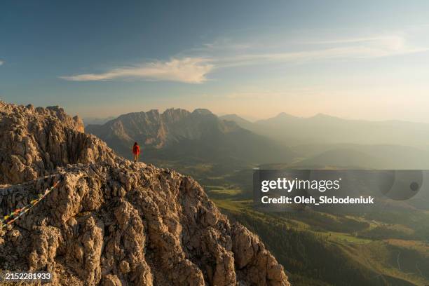 determined woman hiking in extreme terrain and looking at view from the top in dolomites mountains - dolomites stock pictures, royalty-free photos & images