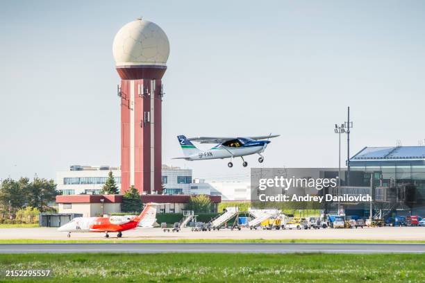 un avión monomotor despega sobre el edificio de la terminal del aeropuerto de lech walesa contra un cielo azul con nubes. - aviacion fotografías e imágenes de stock