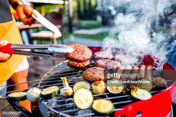 mann beim grillen von fleisch im garten - grillen stock-fotos und bilder