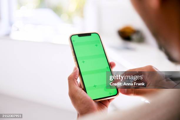 vista posteriore di un uomo che tiene in mano il suo telefono con schermo verde - inquadratura da sopra le spalle foto e immagini stock