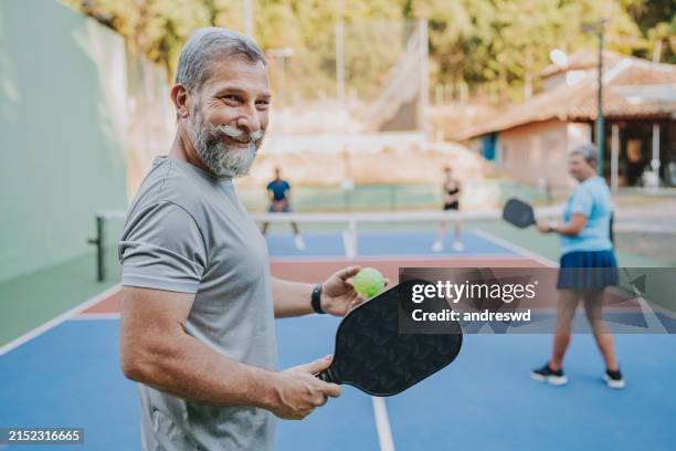 porträt älterer mann, der auf kamera-pickleball-spiel schaut - freizeit sport und spiel stock-fotos und bilder