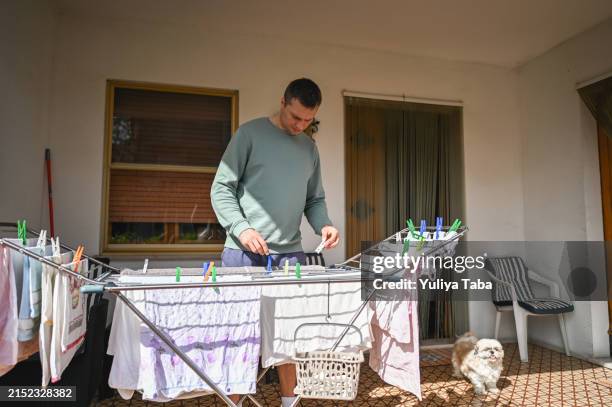 man hanging clothes on clothesline at home terrace. - clothespin string stock pictures, royalty-free photos & images