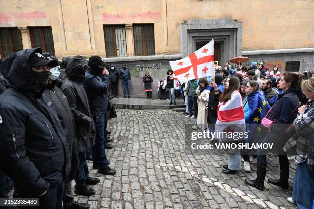 Georgian demonstrators protesting the controversial "foreign influence" bill stand in front of law enforcement officers blocking an area near the...