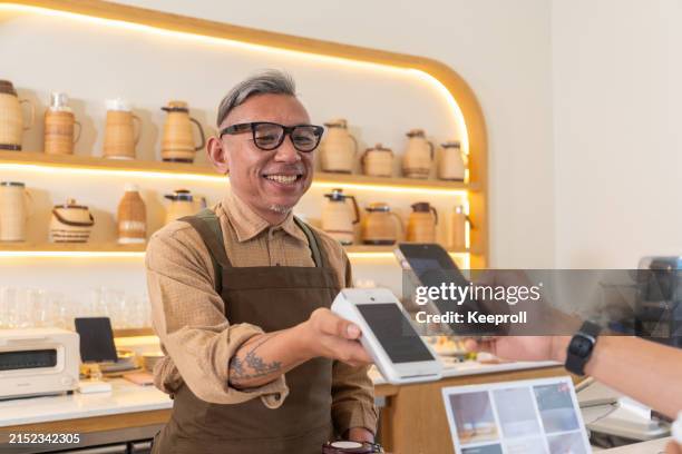 cliente que paga por teléfono - pequeña empresa fotografías e imágenes de stock