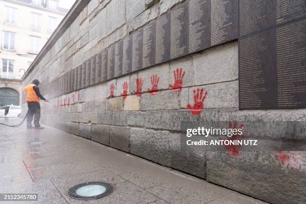 City employee is at work to clean the "Wall of the Righteous" covered with Red hands graffitis outside the Shoah memorial in Paris, on May 14 after...