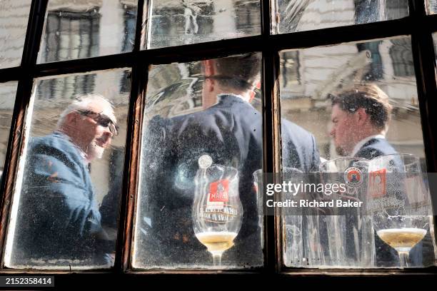 Three businessmen and their near-empty glasses of beer are seen through the frosted glass of a pub window, in the City of London, the capital's...