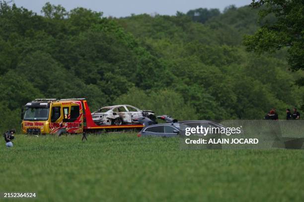 Police officers load of a burnt-out escape car that had been used during a ramming attack which took place late morning at a Incarville's road toll,...