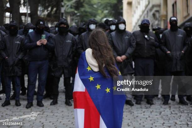 Police officers stand guard as protesters, staging protest, endeavor to breach the security perimeter of the Georgian Parliament building following...