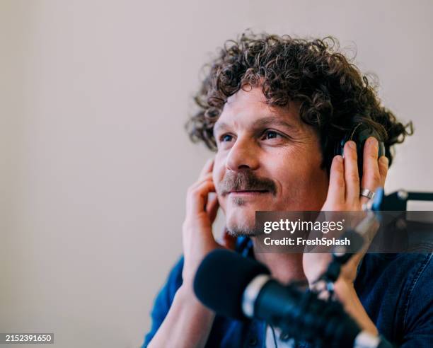 smiling man hosting podcast in professional studio setting - geluidsoverlast stockfoto's en -beelden