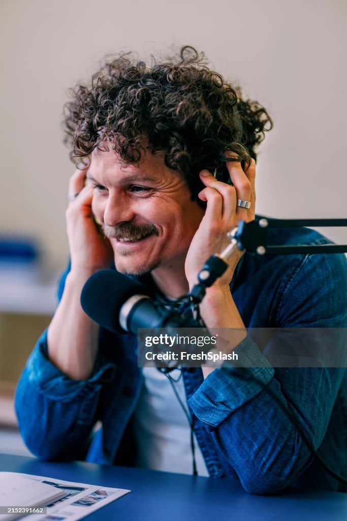 Lockiger Mann genießt Musik beim Podcasting im Studio