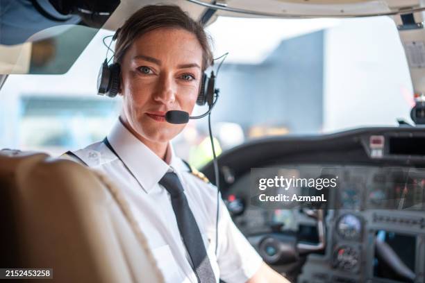 piloto femenina segura de sí misma en la cabina del avión - pilotar fotografías e imágenes de stock