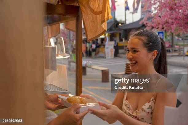 young woman taking takeaways food from street food concession stand. - asiático de asia sudoriental fotografías e imágenes de stock