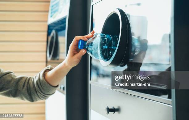 woman recycling plastic bottle via reverse vending machine - ecoponto de reciclagem de garrafas imagens e fotografias de stock