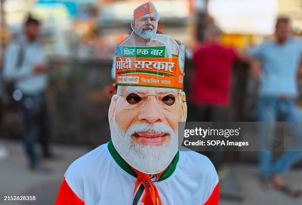 Bharatiya Janata Party supporter wearing a Narendra Modi mask poses for a photo ahead of India's Prime Minister Narendra Modi's roadshow in Mumbai....