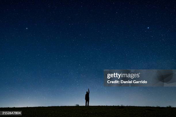 human silhouette pointing with index finger at the starry sky. - sternenhimmel stock-fotos und bilder