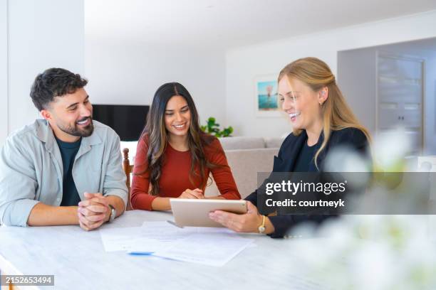 insurance, finance or real estate agent with couple looking through documents. the agent is holding a digital tablet. - schulden stock-fotos und bilder