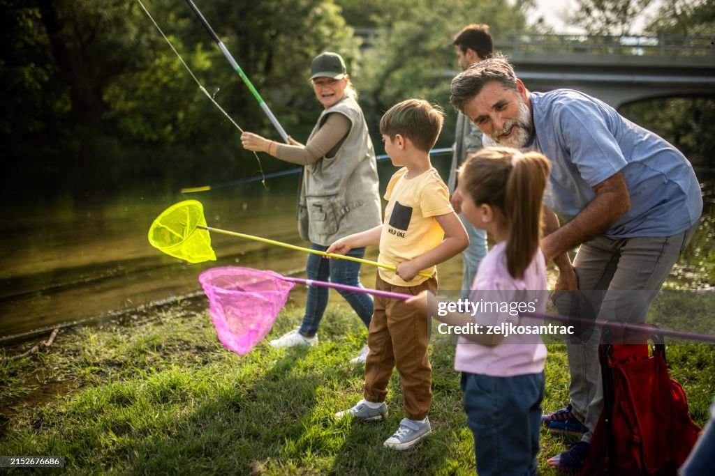 A multigenerational family is camping and they fish in the river
