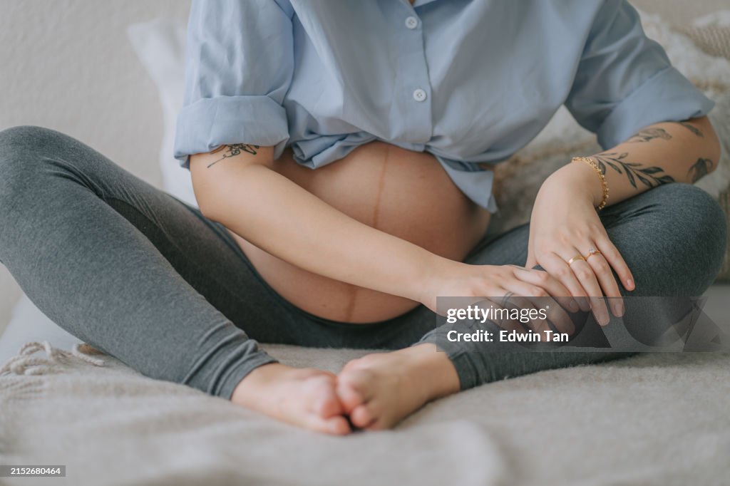 Asian Chinese Pregnant Woman hands massaging her feet painful from cramp ache