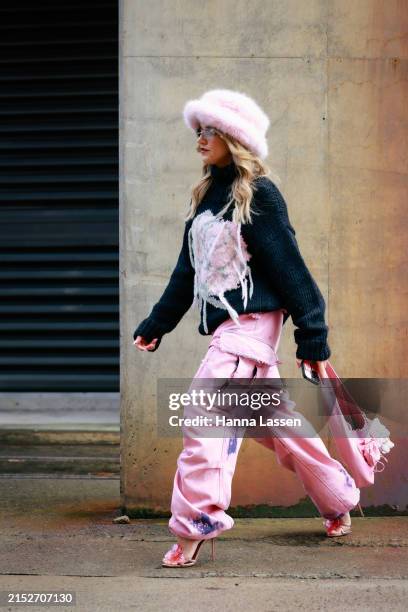 Maxine Wylde wearing pink fur bucket hat, black knit jumper and pink denim tie-dyed pants Australian Fashion Week Presented By Pandora 2024 at...