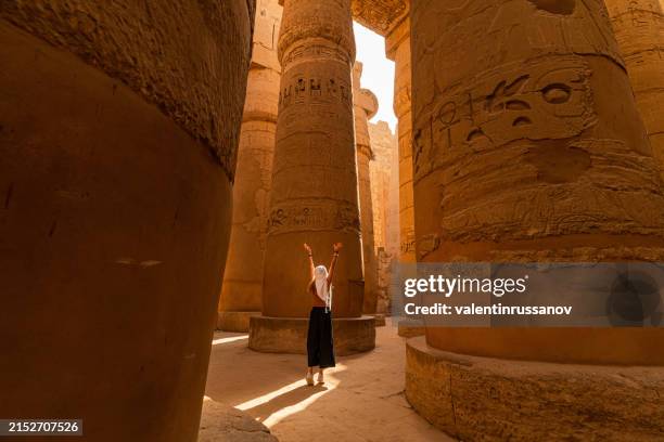 female tourist walks between pillars of the great hypostyle hall from karnak temple - temples of karnak stock pictures, royalty-free photos & images