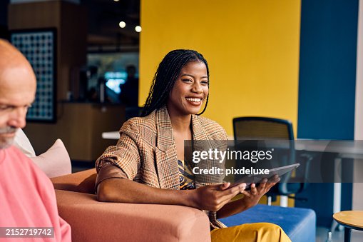 Smiling African American businesswoman in a plaid blazer holding a tablet in a modern office. Empowerment and professional growth in business concept Smiling African American businesswoman in a plaid blazer holding a tablet in a modern office. Empowerment and professional growth in business concept