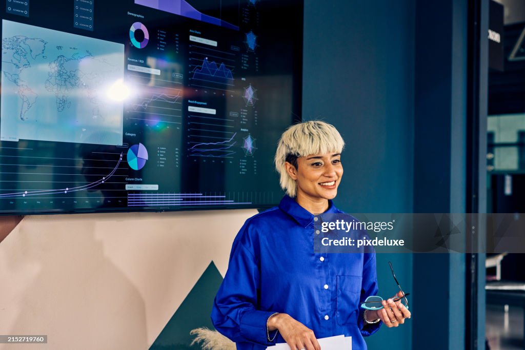 Professional Asian woman presenting data on a digital display in a corporate office. Effective communication and data visualization concept
