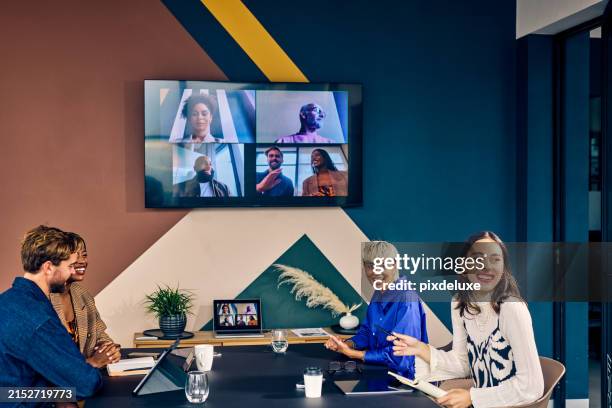 team members in a modern office engaging with remote colleagues via a video conference call. hybrid work environment and digital communication concept - ver stockfoto's en -beelden