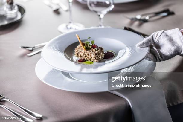 a waiter in white hygienic gloves serves an appetizer, a liver pâté, on a festively laid wedding table. the creatively prepared appetizer is served on a white plate. - pate stock pictures, royalty-free photos & images