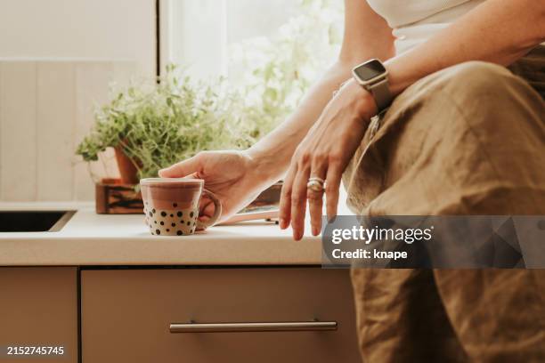 woman at home indoors in her kitchen drinking coffee - wristwatch stock pictures, royalty-free photos & images