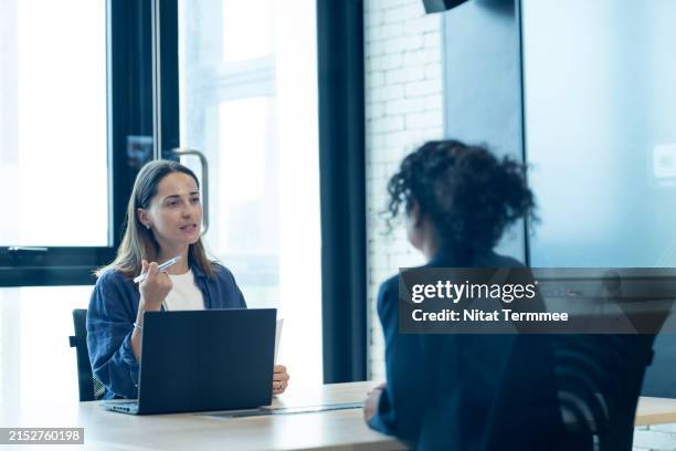 forecast future talent needs with strategic workforce planning. hr manager conducting an interview and considering women for a new hire in a meeting room of a modern business office. - recruiter stockfoto's en -beelden