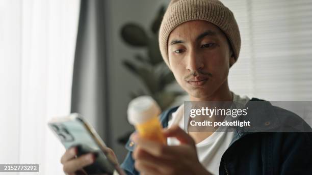 asiatischer mann patient sucht pillen informationen. - verschreibungspflichtiges medikament stock-fotos und bilder