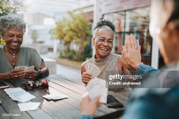 senior women friends playing cards - seniors card table stock pictures, royalty-free photos & images