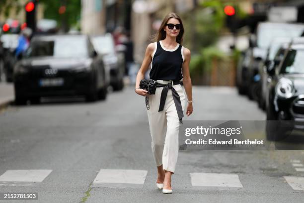 Segolene Hyppolite wears sunglasses, red lipstick / make-up, a dark navy blue / black and white tank top from Tara Jarmon, a black Chanel bag with...