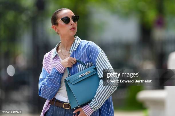 Gabriella Berdugo wears sunglasses, a necklace, a purple and blue striped oversize colored shirt from Ralph Lauren, a white tank top, a brown leather...