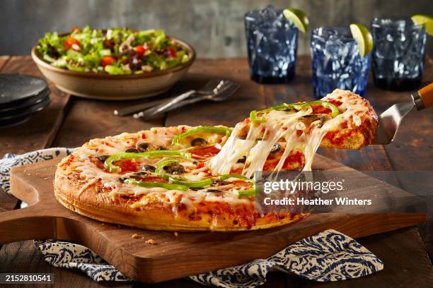pepperoni and vegetable pizza with slice being pulled out - cheese stretch stock pictures, royalty-free photos & images