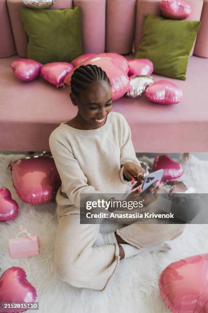 beautiful african american woman calls on the phone and thanks for the romantic surprise. - gift lounge stock-fotos und bilder