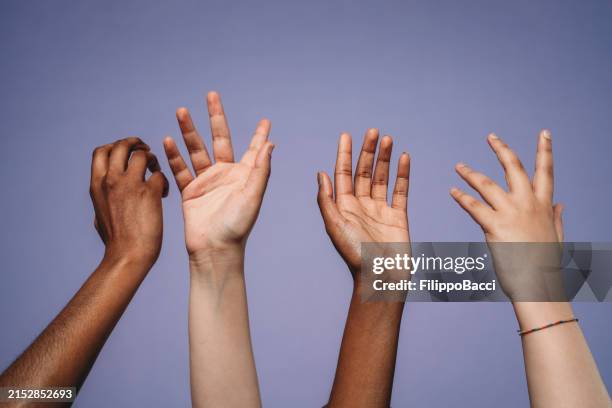 four hands up against a purple background - arms raised stock pictures, royalty-free photos & images