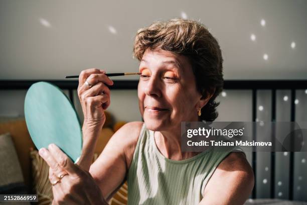 an older woman does her makeup and gets ready for a party. - eye make up stock pictures, royalty-free photos & images
