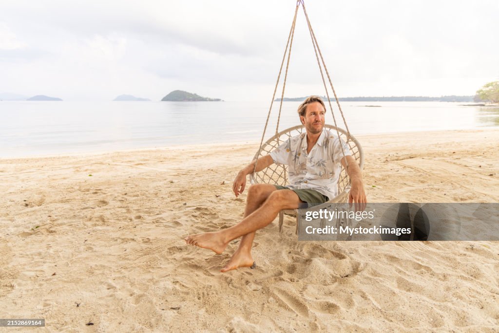 Man Relaxing in a Swing Chair on the Beach